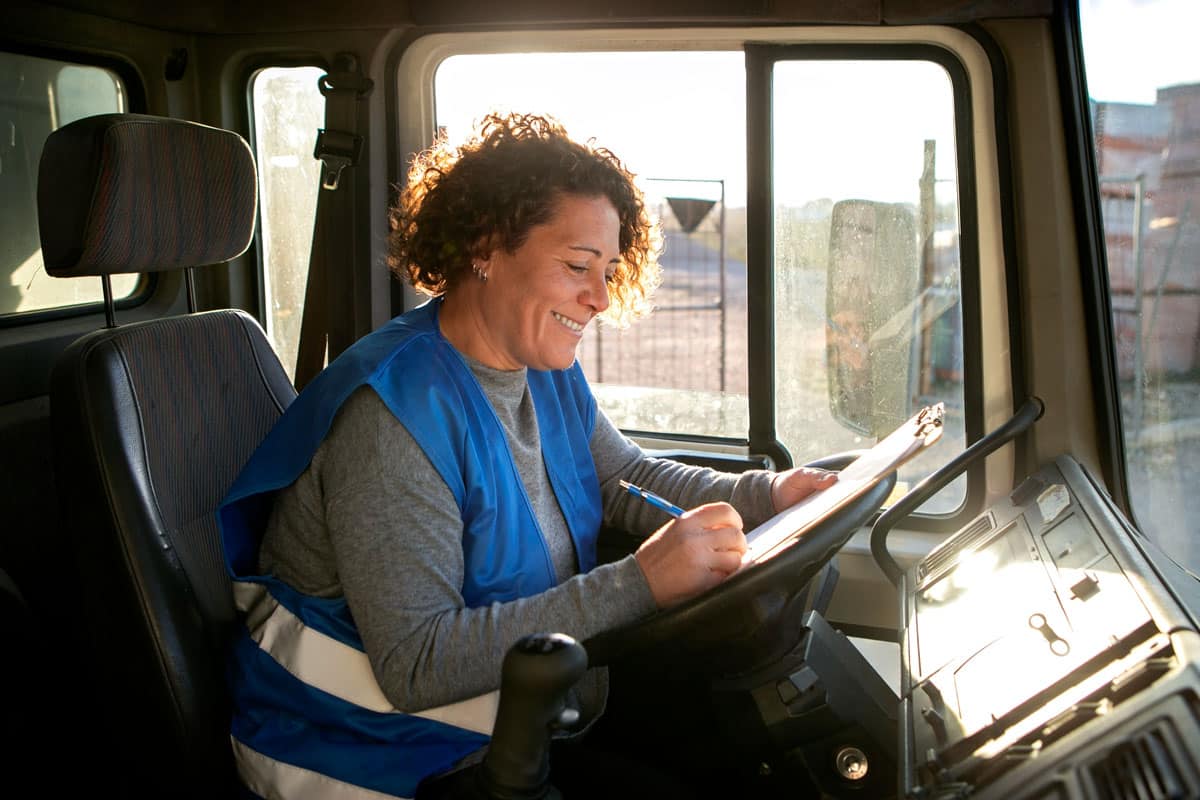 Older female truck driver (logistics company) filling out a safety communications report for CommsKit